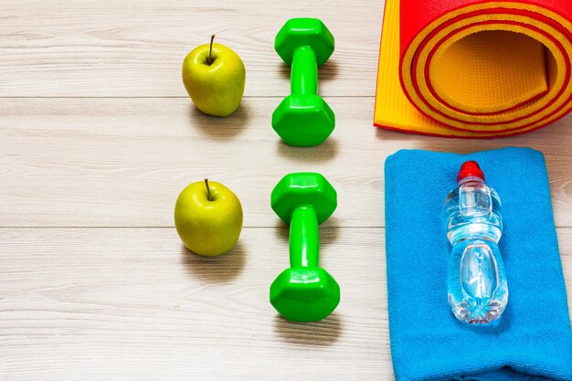 Yoga mat and different tools for fitness on floor in room