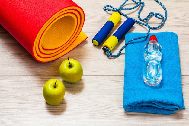 Yoga mat and different tools for fitness on floor in room