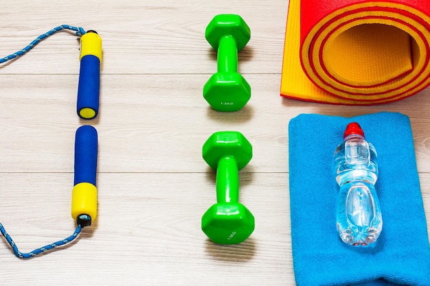 Yoga mat and different tools for fitness on floor in room