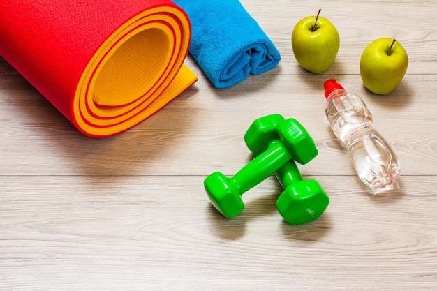 Yoga mat and different tools for fitness on floor in room