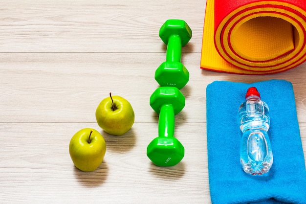 Yoga mat and different tools for fitness on floor in room