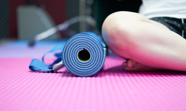 Фото Коврик для йоги на полу рядом с сидением, скрестив ноги, на корточках на полу в помещении в спортивной одежде