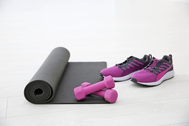 Photo yoga mat sneakers and dumbbells on light background