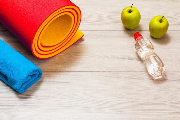 Коврик для йоги и инструменты для фитнеса на полу в комнате