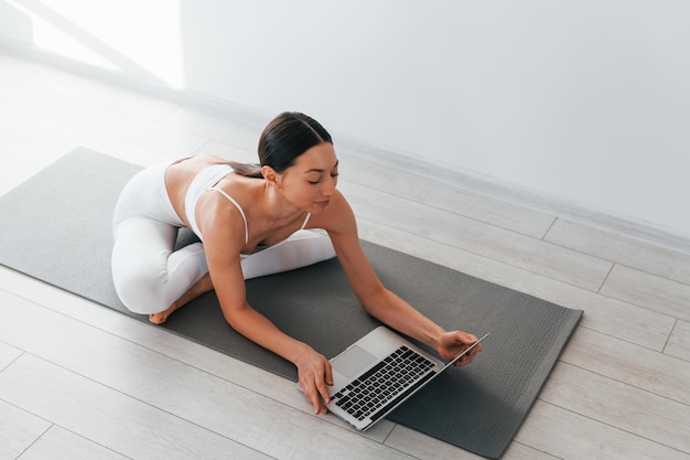 On yoga mat Young caucasian woman with slim body shape is indoors at daytime