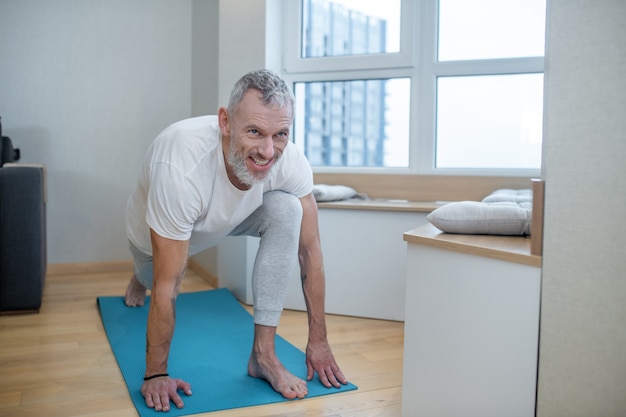 Yoga. A mature man practising yoga at home and looking concentrated