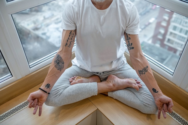 Yoga. A mature man in a white tshirt doing yoga and looking concentrated