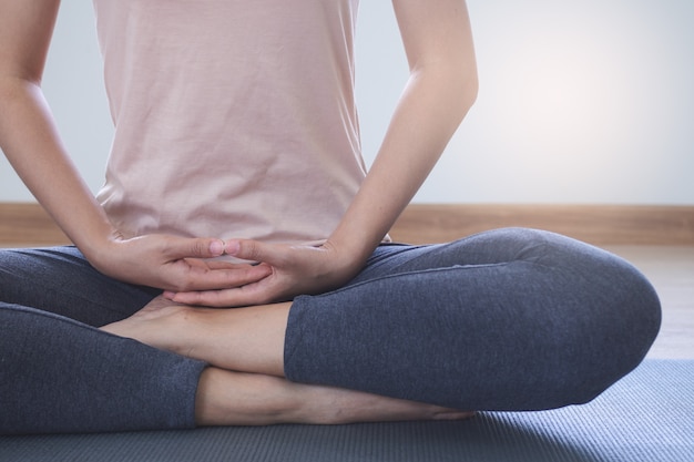 Foto stili di vita di yoga e meditazione. vista ravvicinata della giovane e bella donna praticare yoga namaste posa nel salotto di casa.