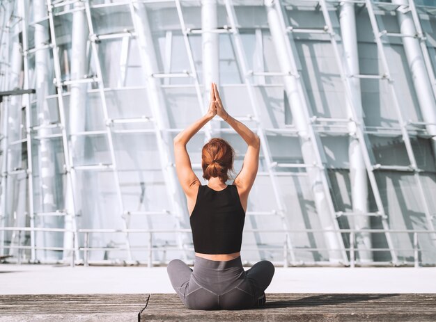 Yoga e meditazione nella città moderna vista posteriore della donna che medita e fa esercizi di respirazione