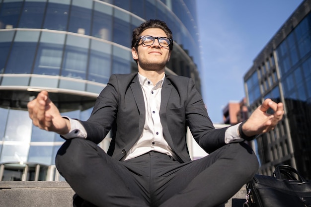 Йога-медитация снимает стресс у менеджера-мужчины в деловом костюме