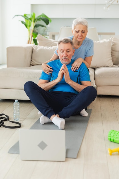 Foto yoga mindfulness meditazione anziani adulti coppia matura che pratica yoga con lezioni online nel portatile