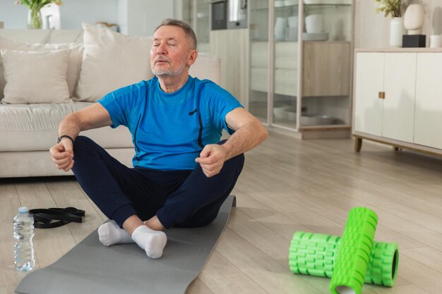 Yoga mindfulness meditation senior adult mature man practicing yoga at home mid age old grandfather