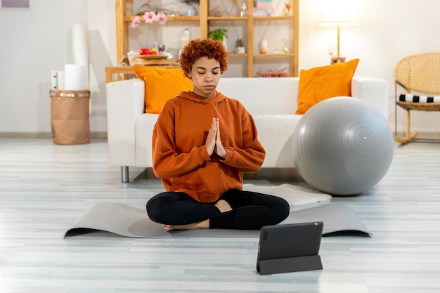 Yoga mindfulness meditation young healthy african girl practicing yoga at home woman sitting in lotu