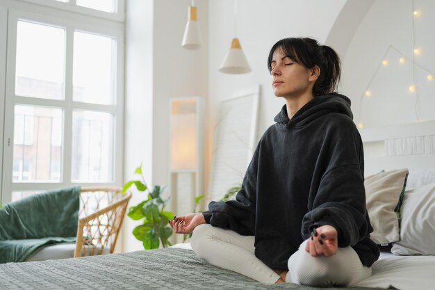Photo yoga mindfulness meditation young healthy woman practicing yoga in bedroom at home woman sitting in