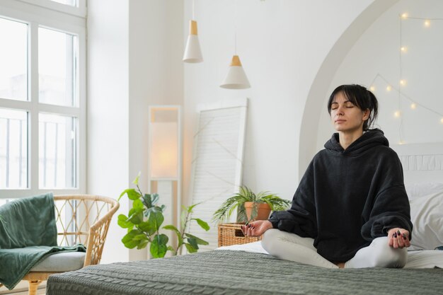 Photo yoga mindfulness meditation young healthy woman practicing yoga in bedroom at home woman sitting in