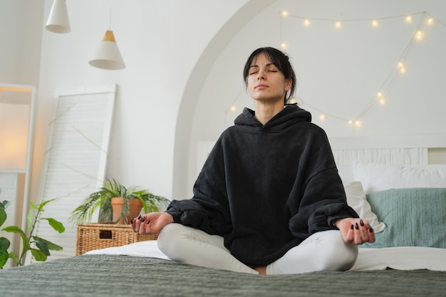 Photo yoga mindfulness meditation young healthy woman practicing yoga in bedroom at home woman sitting in