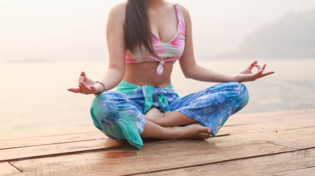 Yoga op het strand Gelukkige Aziatische vrouw die Tie Dye-bikini draagt die yoga beoefent Jonge gezonde vrouw op zomeryoga bij zonsondergang seashorexA