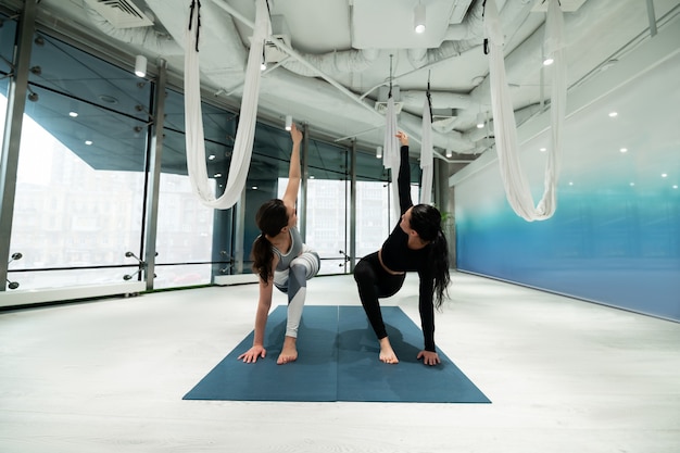 Yoga op matten. Twee fitte vrouwen met paardenstaarten die een legging dragen terwijl ze samen yoga doen op sportmatten