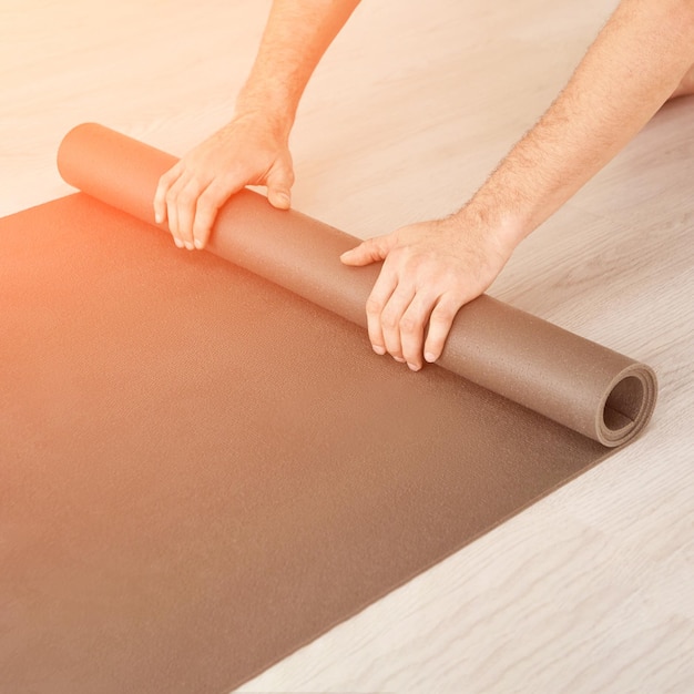 Yoga persoon rollende sport mat grijze kleur sportschool tapijt armen roll pad close-up concept met copyspace aerobics mat fitness club vloer mannelijke nands leraar klasse achtergrond