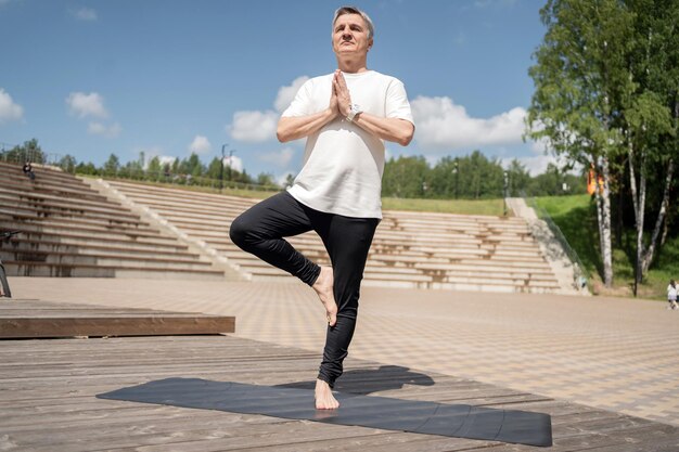 Yoga pose asana balance and harmony old adult man gray hair\
fitness workout in the park exercise