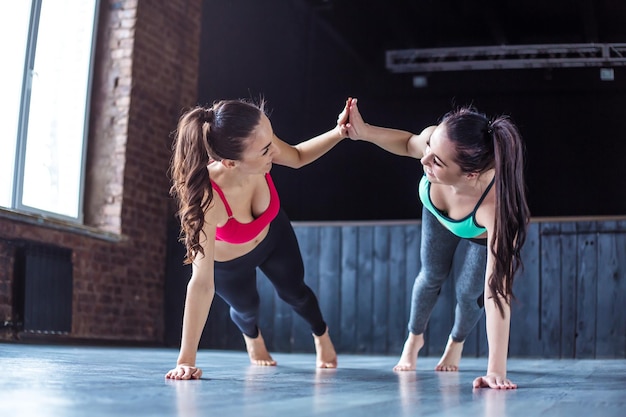 Yoga positions Beautiful smiling women working out in gym together Sport yoga healthy lifestyle