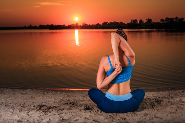 yoga at sunset on the beach. woman doing yoga, performing asanas and enjoying life on the river