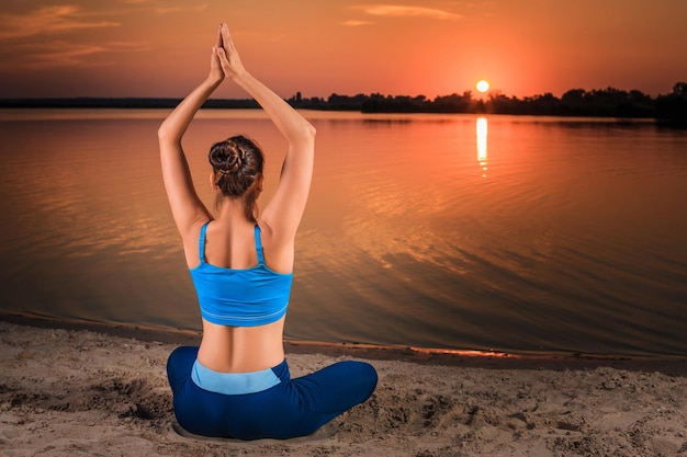 yoga at sunset on the beach. woman doing yoga, performing asanas and enjoying life on the river