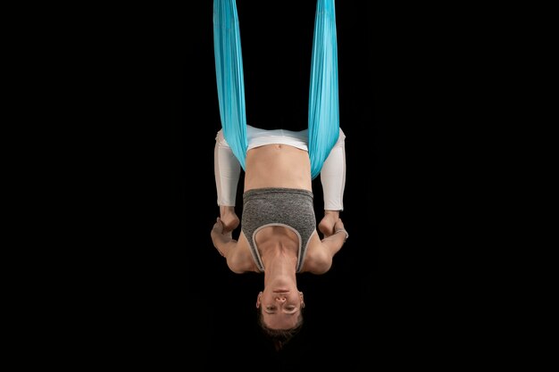 Yoga teacher in class demonstrates inverted asanas during fly yoga Girl practices antigravity yoga upside down