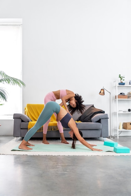 Yoga teacher correcting a downward facing dog pose to her student