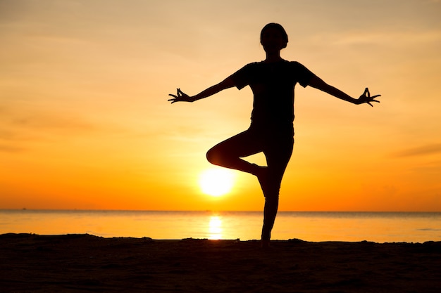 Yoga vrouw silhouet met zonsopgang in de ochtend.