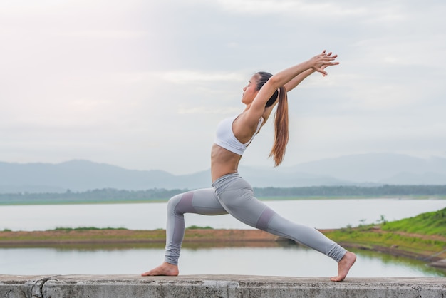 Yoga woman doing exercise at the river in the morning.