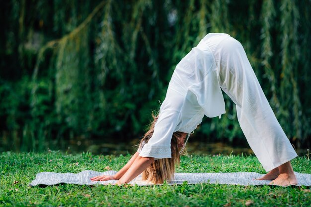 Photo yoga woman doing yoga by the lake green background