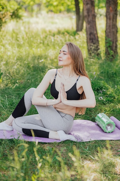 Yoga donna su erba verde ragazza si rilassa nel campo yoga donna nel parco verde ragazza che fa ginnastica all'aperto meditando donna in meditazione in posa yoga pratiche all'aperto