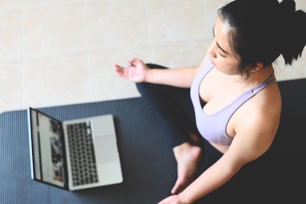Йога женщина в домашней йоге онлайн обучение инструктор по йоге поза урок дыхание медитация упражнения тренировки в спортивной одежде женщины тренируются дома хорошее самочувствие молодой практикующий в помещении