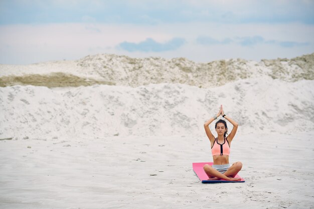 Donna di yoga che si distende dal mare all'alba