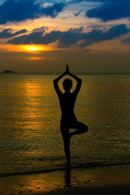 Yoga women silhouette working on poses at sunset