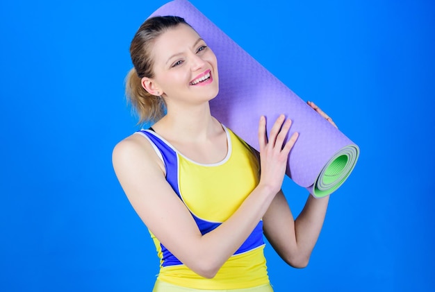 Yogales concept Yoga als hobby en sport Elke dag yoga beoefenen Meisje slim fit atleet houdt fitnessmat vast Fitness en rekken Strekken spieren Grote vooruitgang Atleet yoga coach