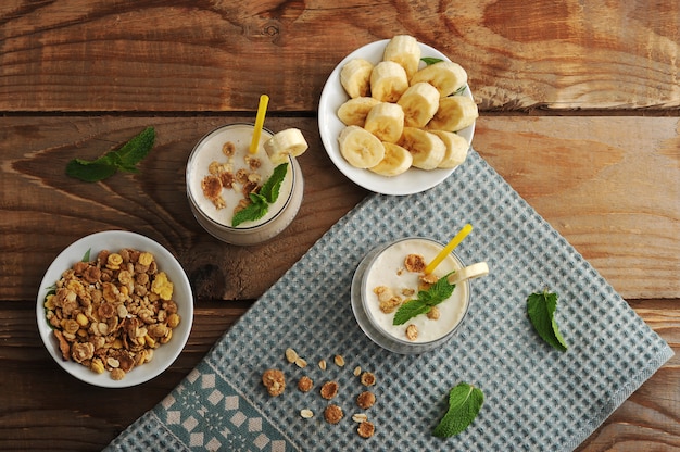 Yoghurt in cups with a straw with muesli and banana