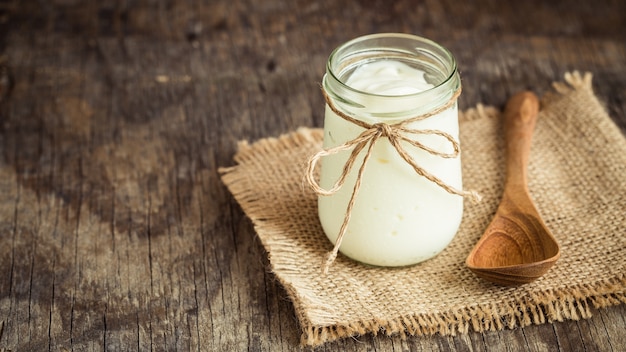 Yoghurt in glasflessen op oude houten lijst