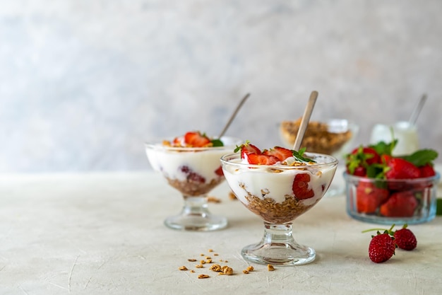 Yoghurt met aardbeiencompote en granola met vers fruit in dessertbekers Gezond ontbijt