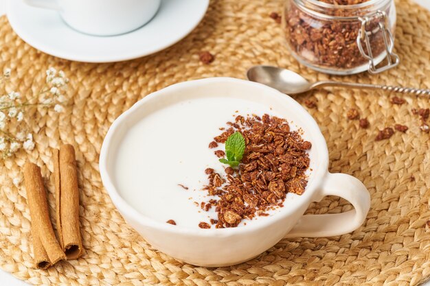 Yoghurt met chocoladegranola in kop, ontbijt met thee op beige