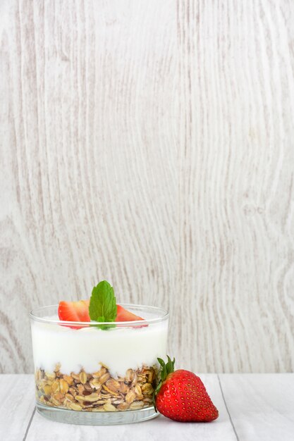 Yoghurt met granen en aardbeien op witte houten tafel kopie ruimte