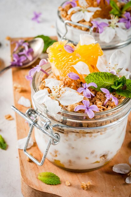 Yoghurt met granola, sinaasappel, munt en eetbare bloemen