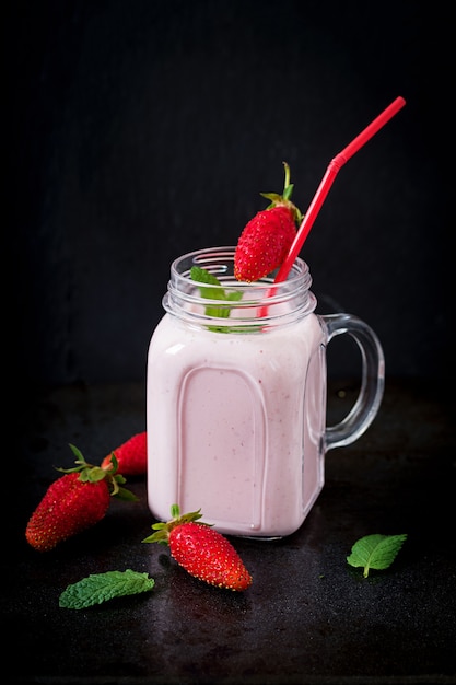 Yoghurt-strawberry smoothies in a jar on a black background