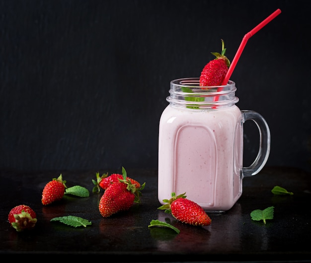 Yoghurt-strawberry smoothies in a jar on a black background