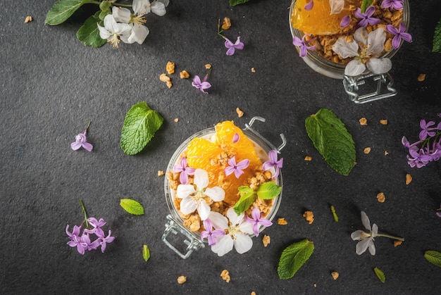 Yoghurt with granola, orange, mint and edible flowers