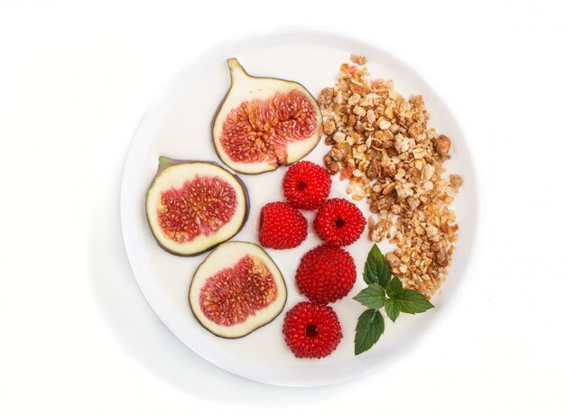 Yoghurt with raspberry, granola and figs in white plate isolated on white background