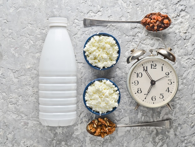 Yogurt bottle, Bowls with cottage cheese, spoons with walnuts and raisins