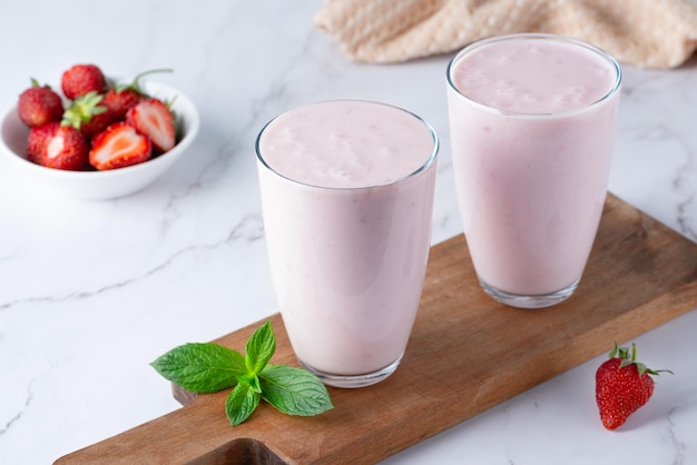 Photo yogurt buttermilk or kefir with strawberry yogurt in glass on light background