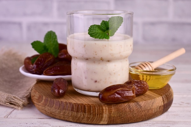 Yogurt and dates and honey in a glass on a wooden board.